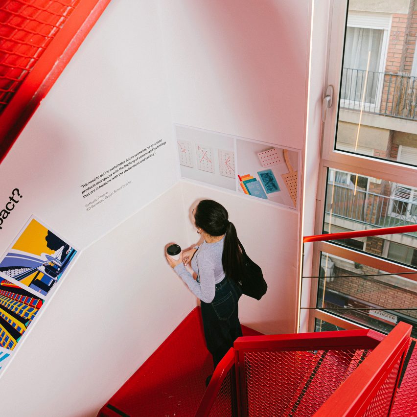 a photograph of a person in a red staircase, looking at work on a white wall