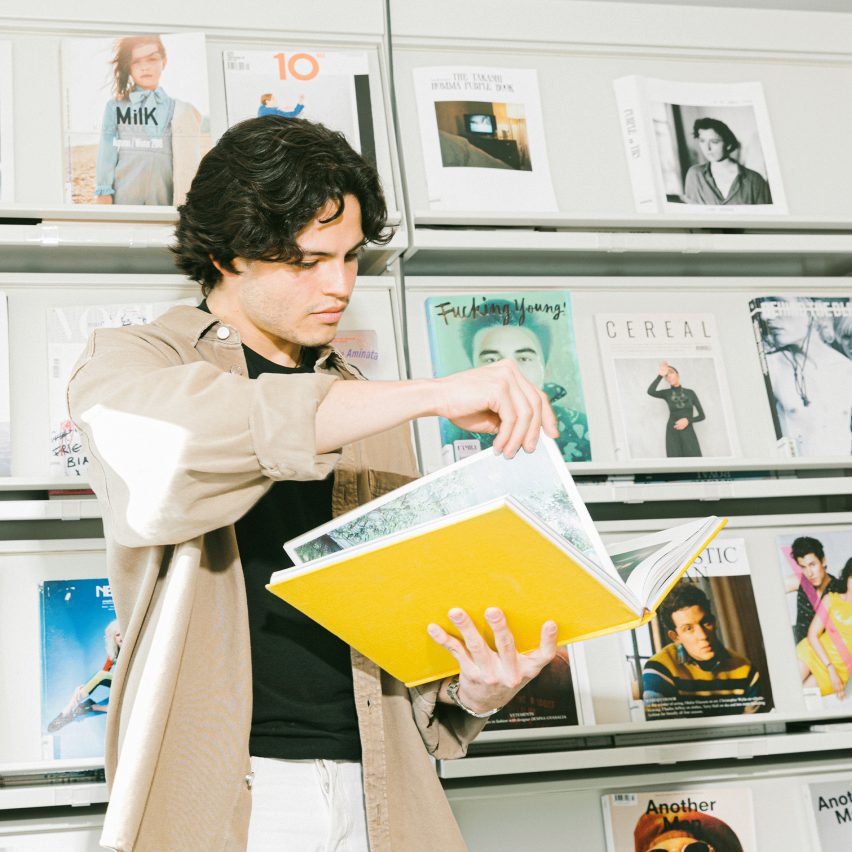 a photo of a person holding a yellow book in front of a bookshelf