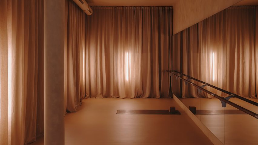 Barre studio with floor-to-ceiling curtains and mirrored walls