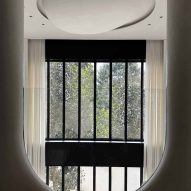 Photograph of an egg-like ceiling sculpture with tall glass windows in the backdrop.