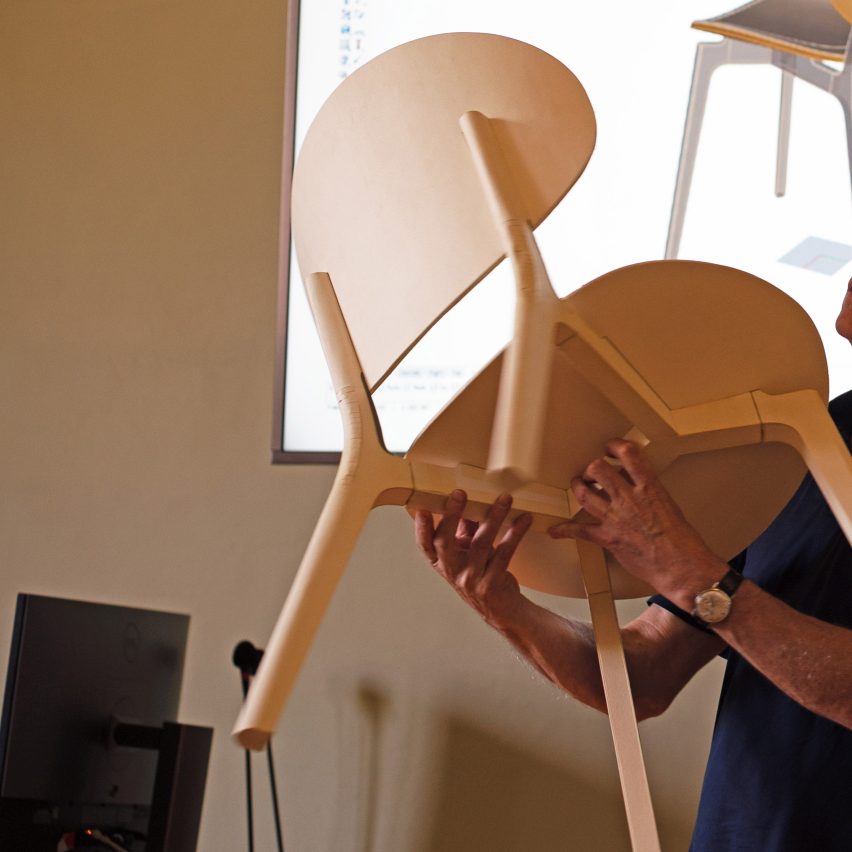 a person's hands holding a wooden chair