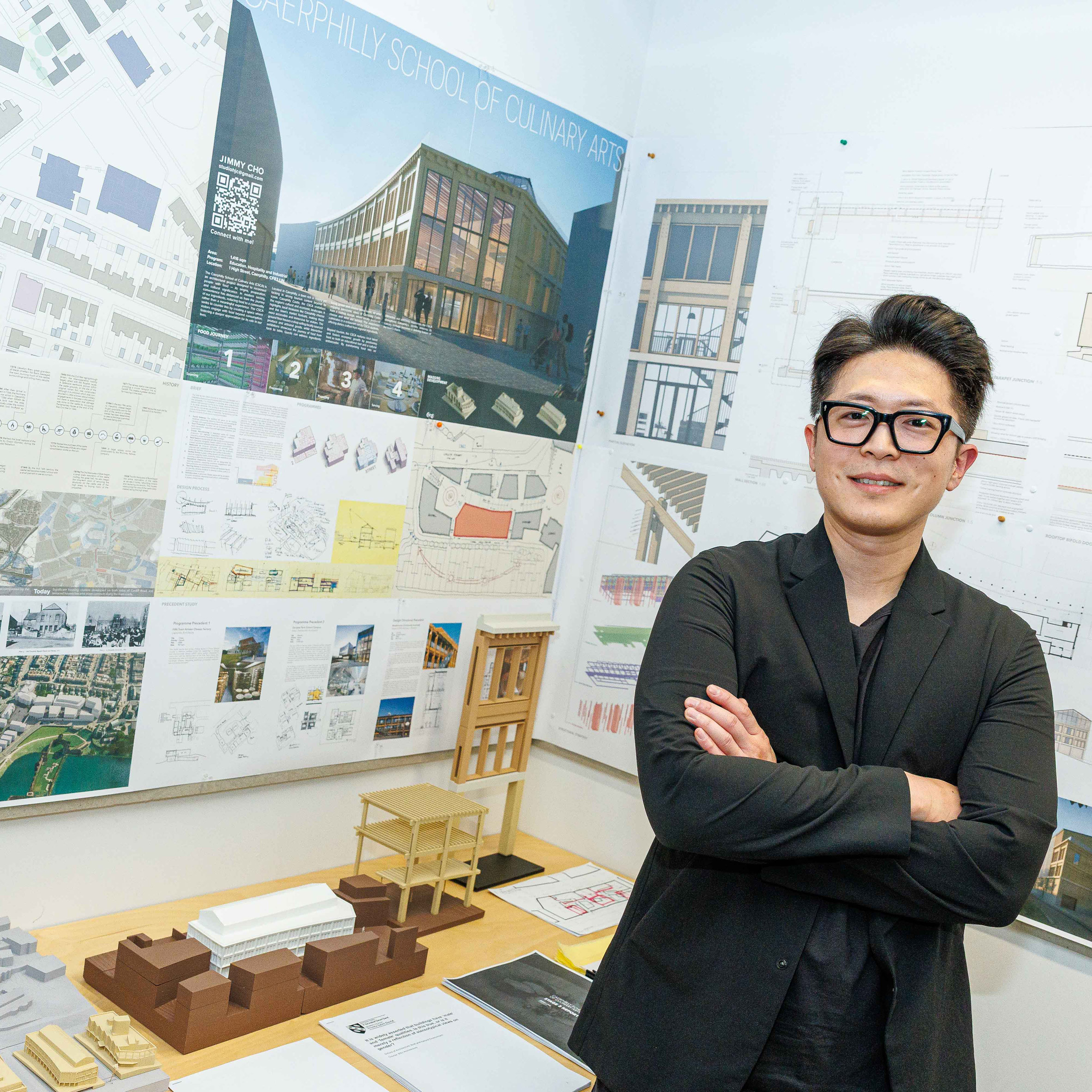 a person standing with student architecture work