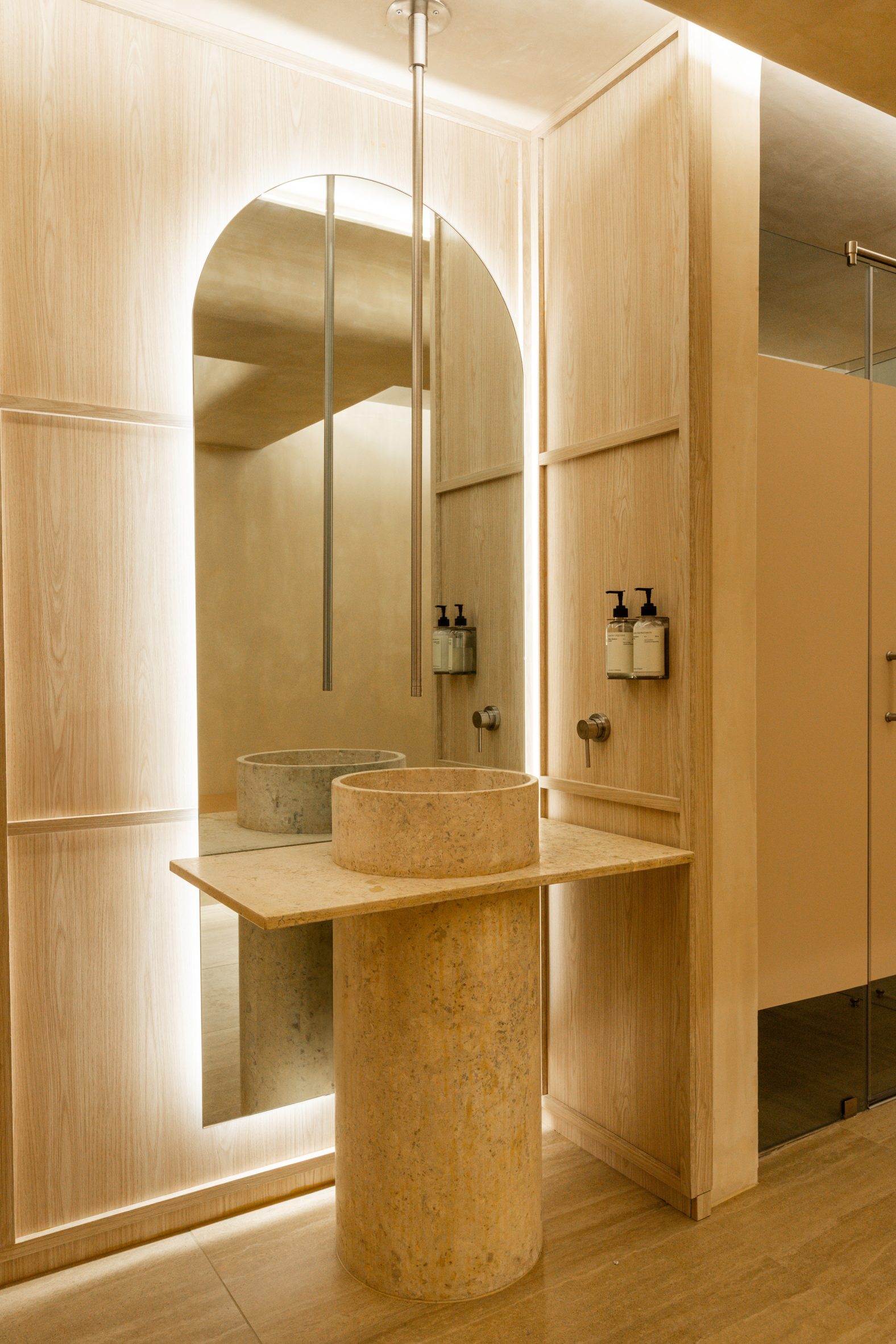 A cylindrical stone basin positioned in front of a large arched mirror