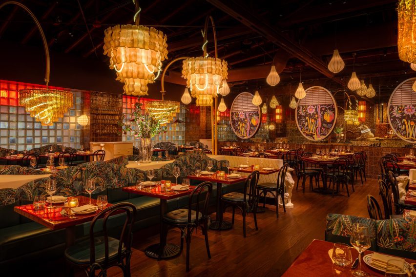 Neon tubes emerge from and spiral within chandeliers throughout a restaurant interior
