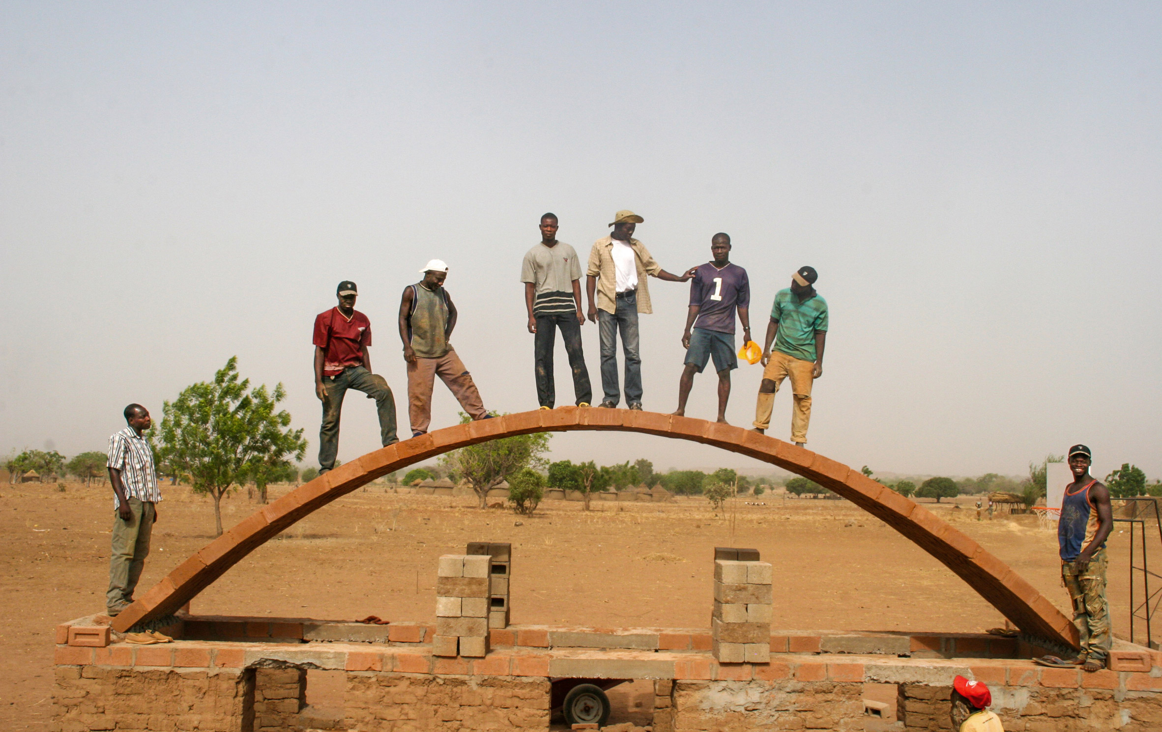 Kéré and builders standing on structural arch 