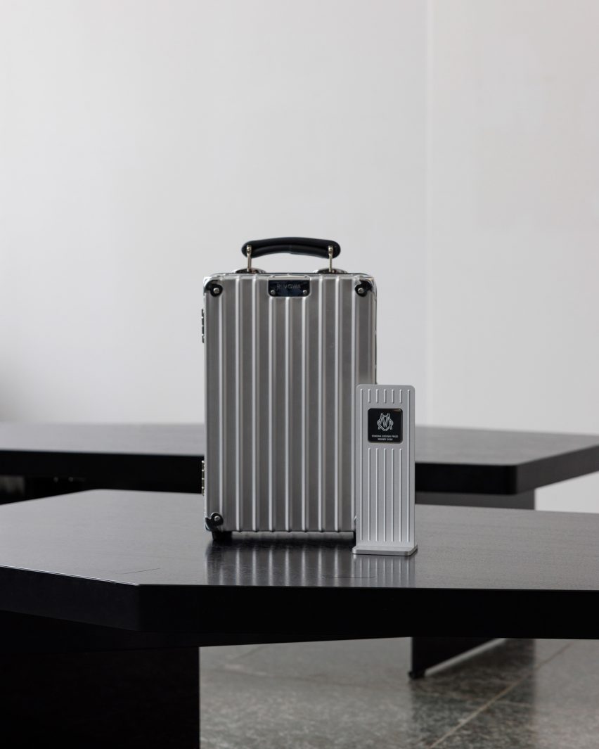 Rimowa suitcases and award trophies displayed on black tables