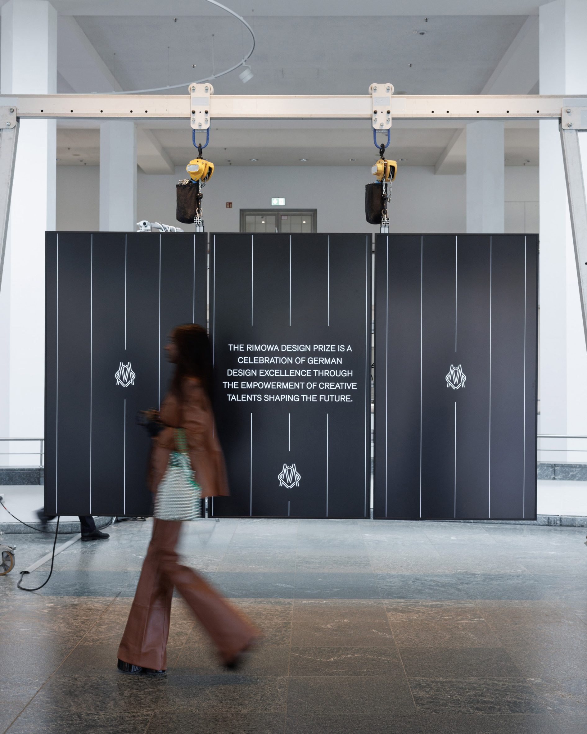 Los visitantes pasan junto a la instalación expositiva del Rimowa Design Award en el gran espacio de la galería