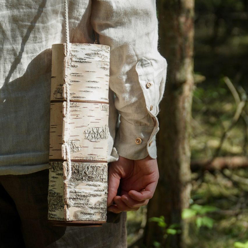 Photograph of a storage container that resembles wooden logs. The container is attached to a string and is being held like a bag.