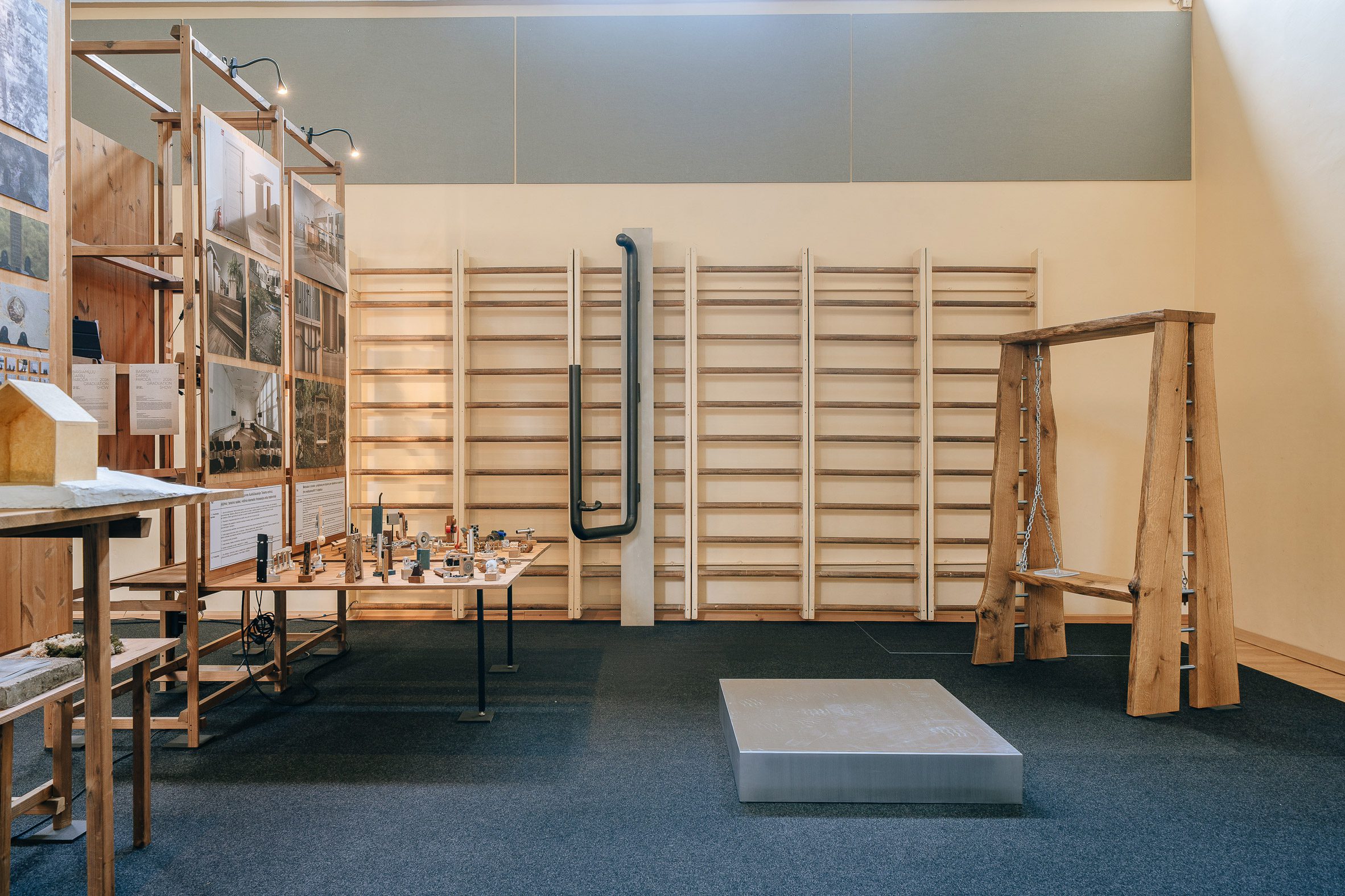 Image of an exhibition station, with small objects on a table and a wooden bench-swing.
