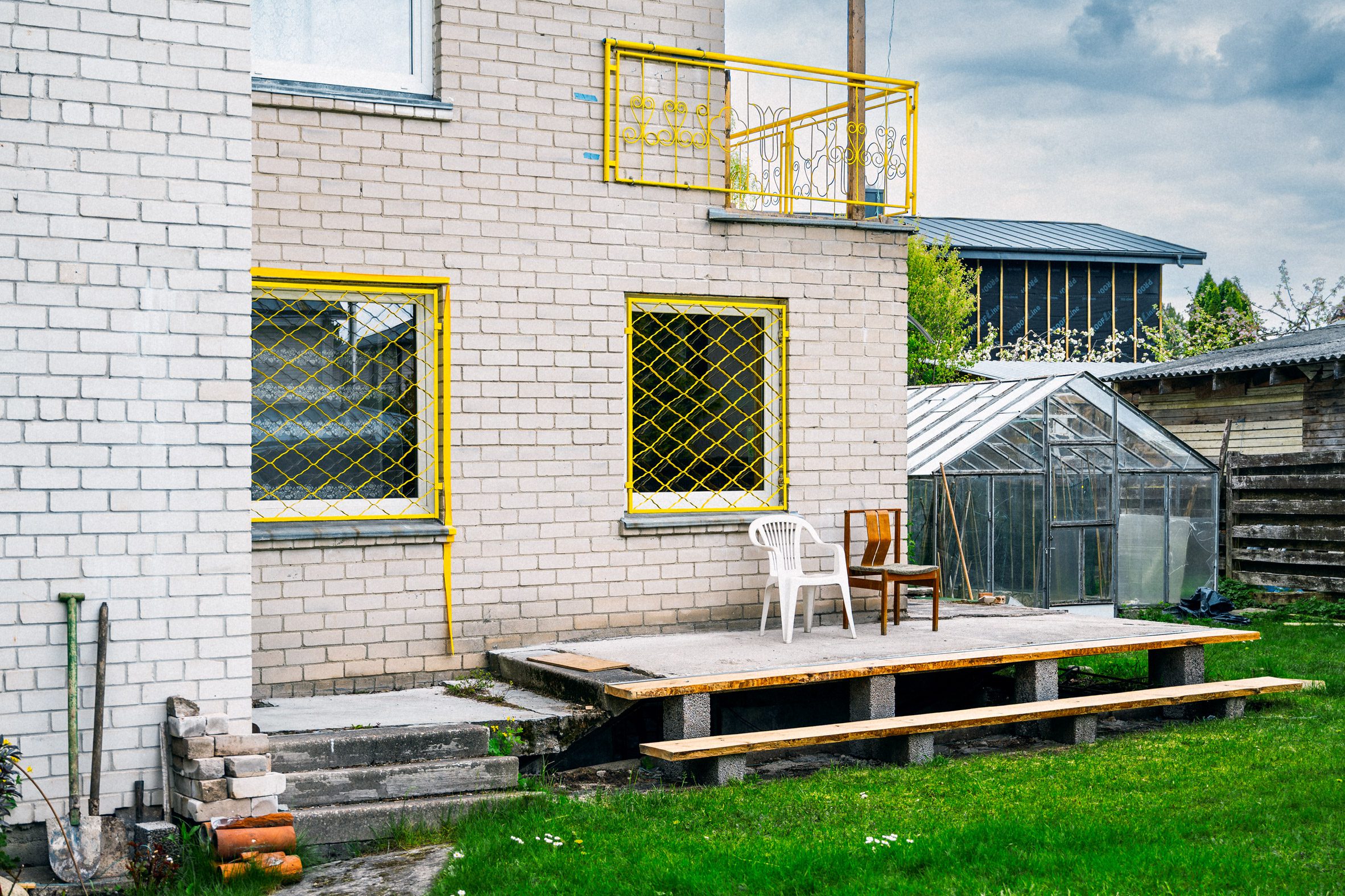 Image of a garden setting with decking, two chairs and windows covered in bright yellow caging.