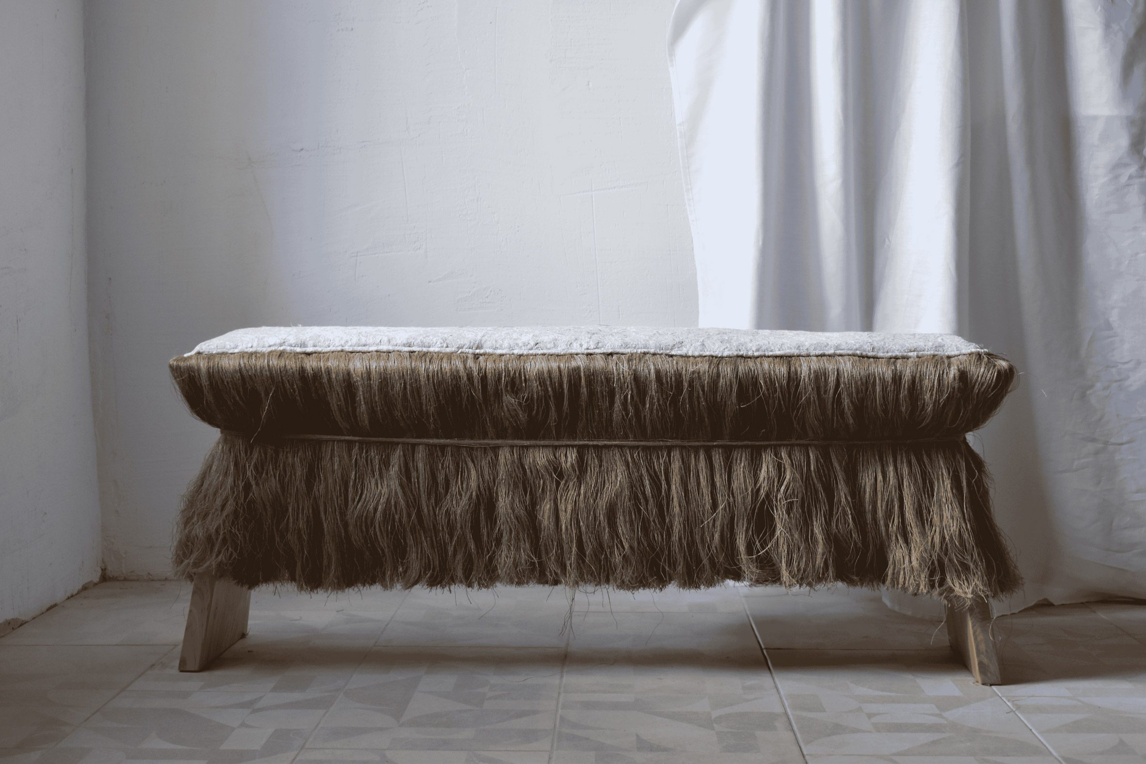 Photograph of a bench with hair-like tassels.