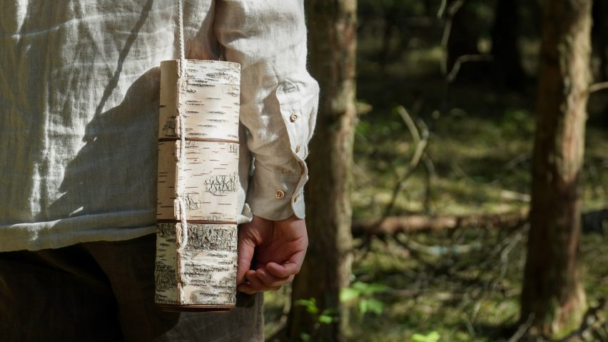 Photograph of a storage container that resembles wooden logs. The container is attached to a string and is being held like a bag.