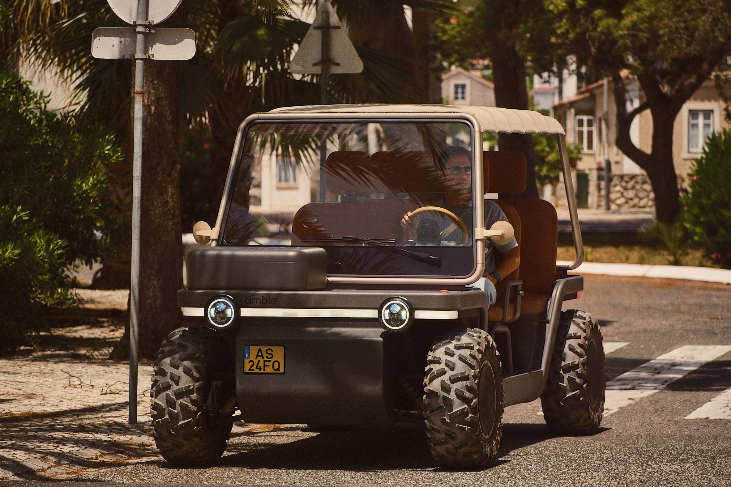 Foto do buggy Amble One em modo street legal com uma caixa em vez de uma cesta na frente, dirigindo por uma rua