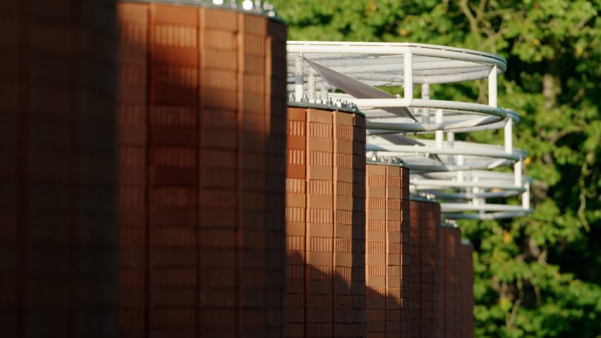 Close-up view of the pavilion showing curved brick walls topped by a white steel canopy structure