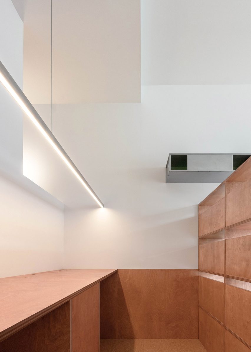A home office tucked behind a plywood shelving unit