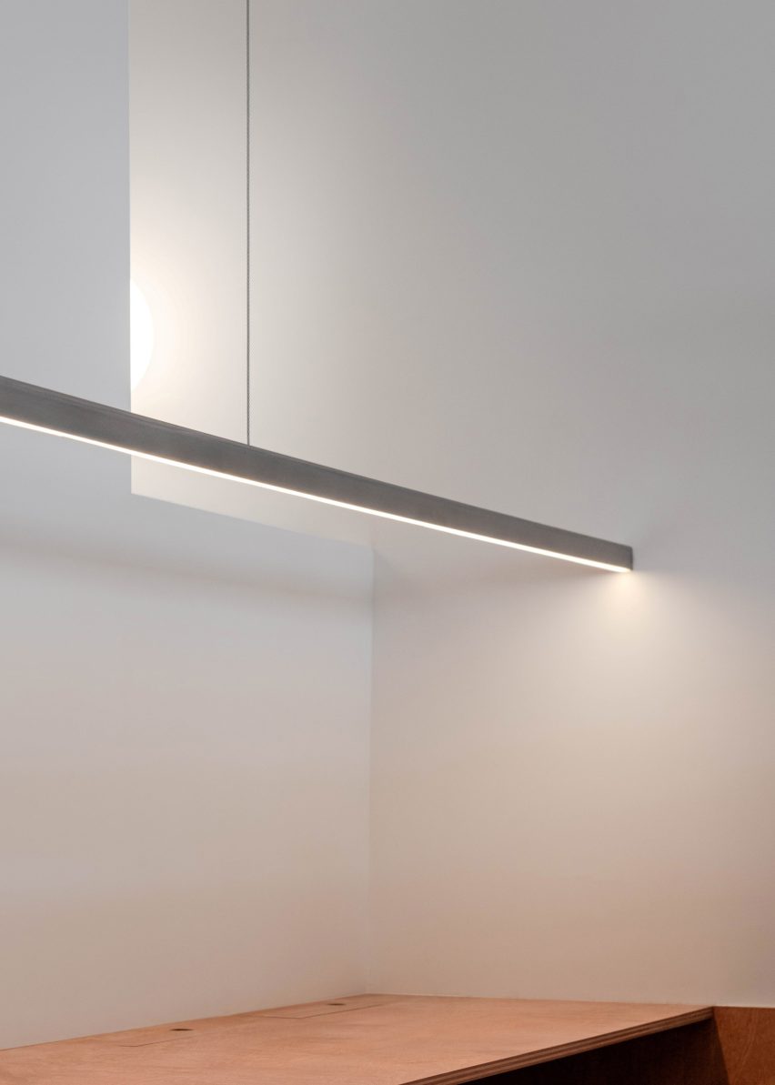 A minimalist horizontal light fixture illuminates a workspace