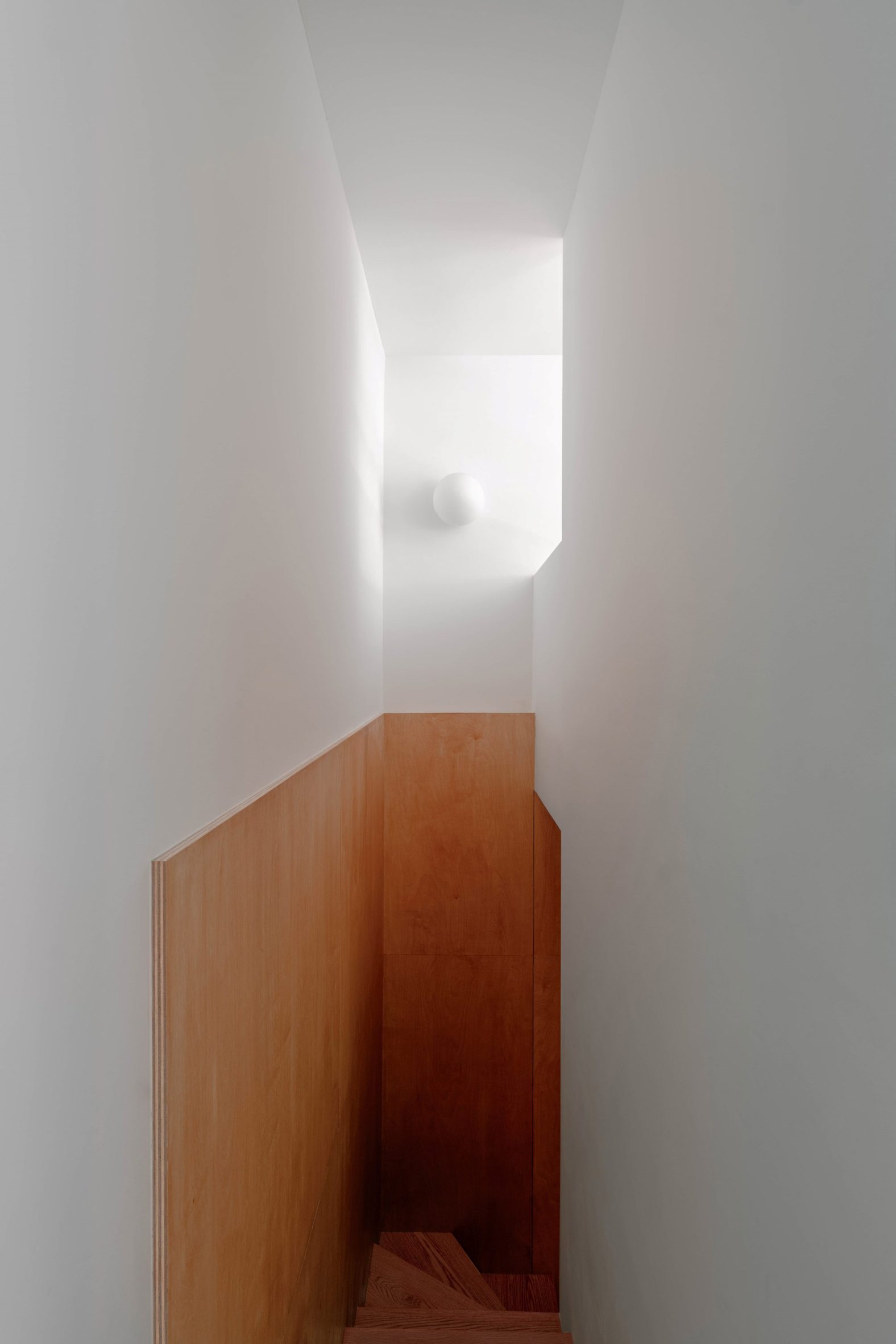 Plywood lines a narrow stairwell that leads to lower-level bedrooms.