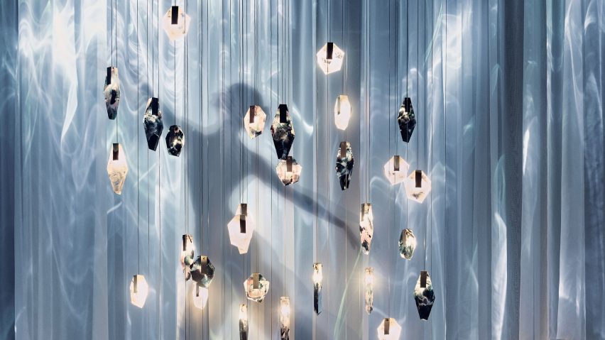 Silhouette of a dancer behind hanging glass lighting pieces and sheer fabric curtains
