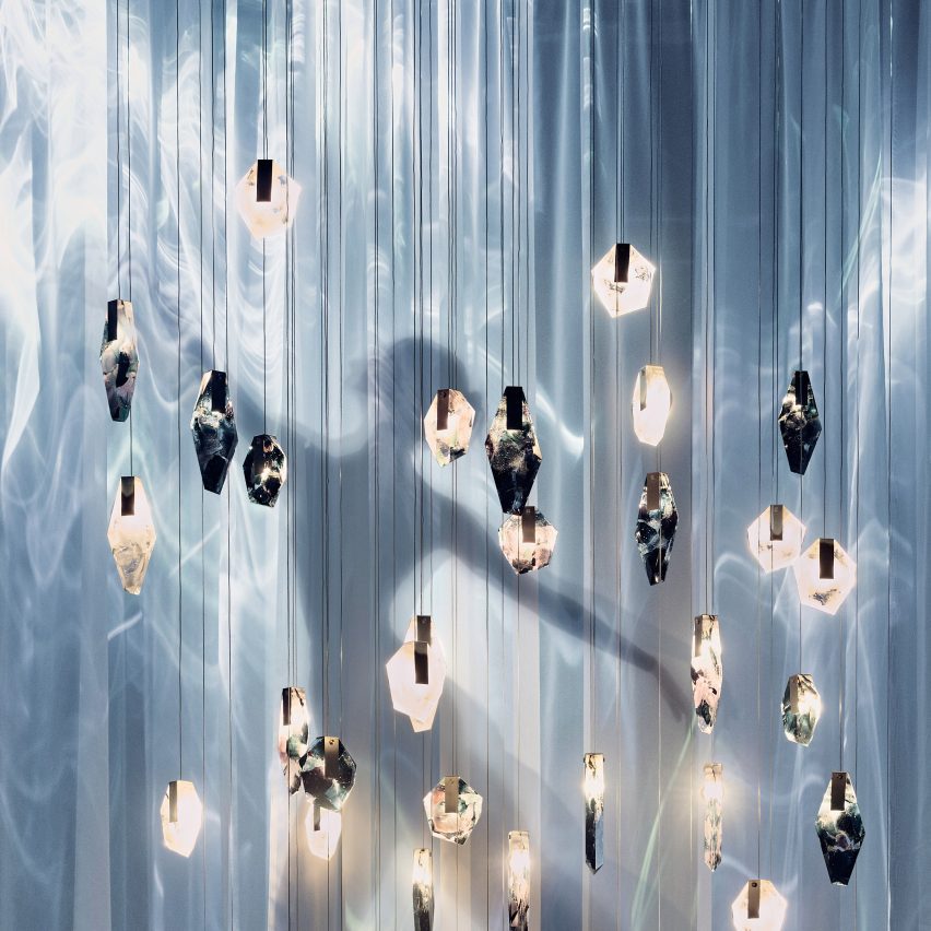 Silhouette of a dancer behind hanging glass lighting pieces and sheer fabric curtains