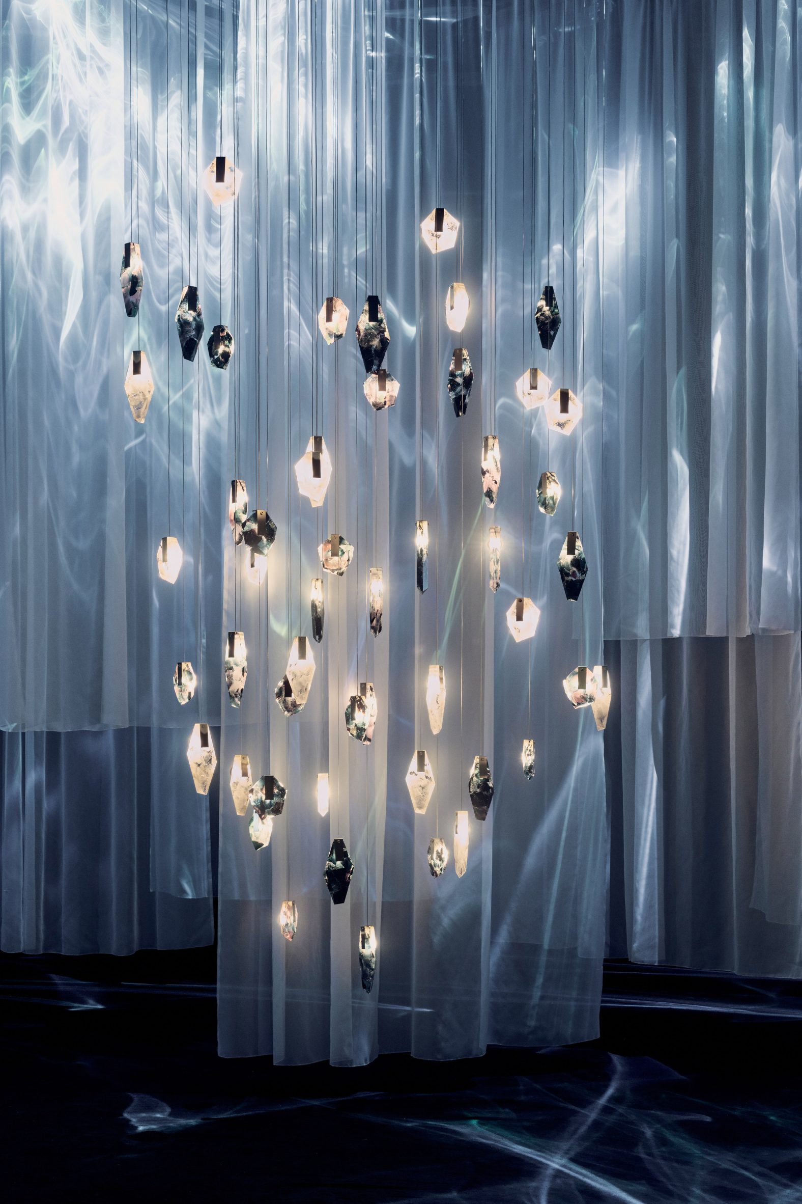 Suspended crystal lighting forms hanging between translucent fabric panels
