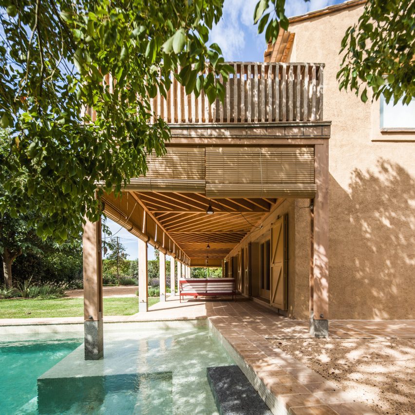 Timber porch with bamboo blinds extending over swimming pool
