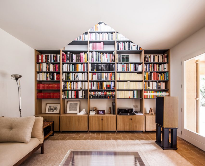 Built-in library shelves framed by a triangular opening in the ceiling