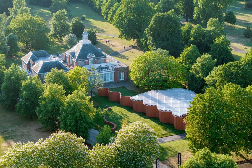 Aerial view of the Serpentine Pavilion showing undulating brick walls and a translucent white roof set among mature trees