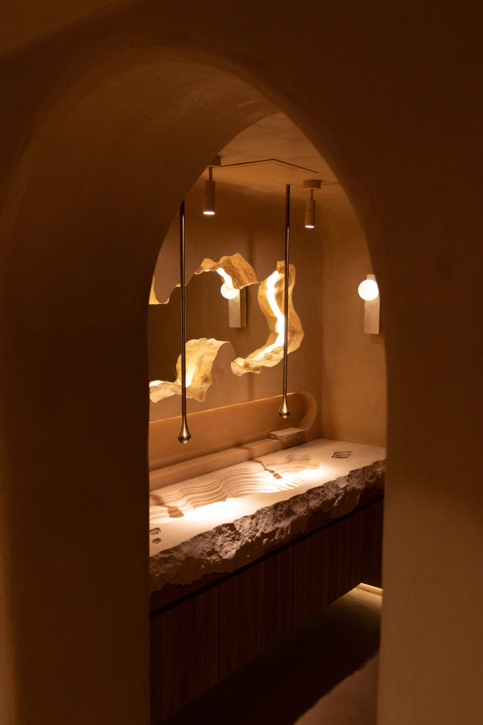 A bathroom featuring a recessed mirror and a rough-edged vanity