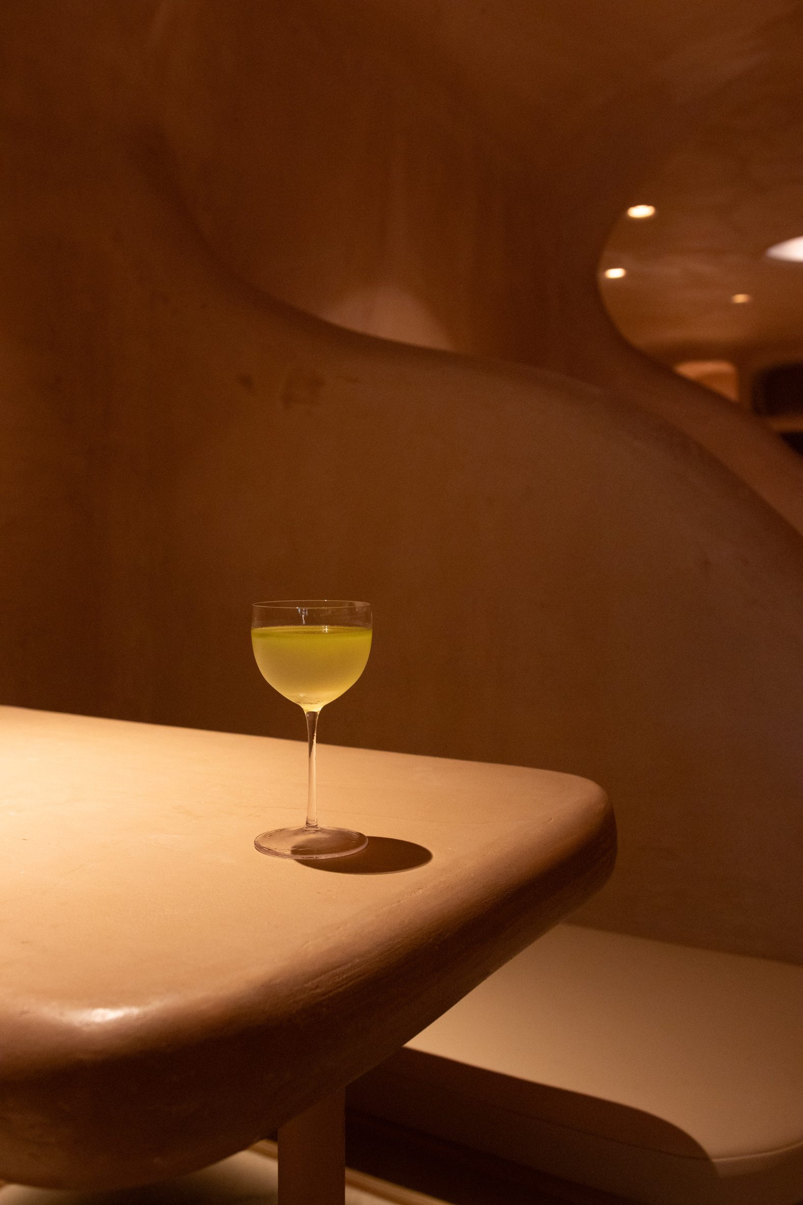A yellow-hued cocktail in a glass on a table