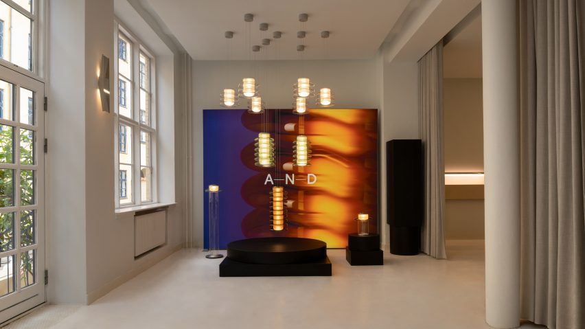 Gallery space with suspended pendant lights and a glowing A-N-D backdrop