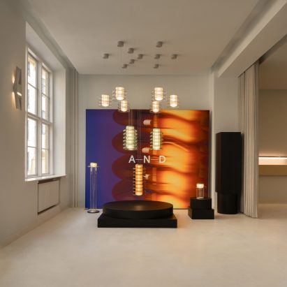 Gallery space with suspended pendant lights and a glowing A-N-D backdrop