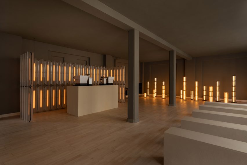 Dark exhibition room filled with glowing vertical floor lamps