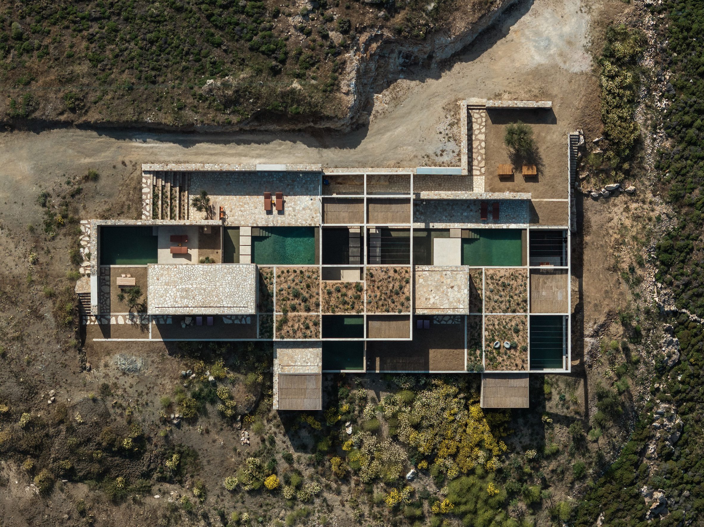 La vista aérea muestra piscinas, techos con plantas y patios dispuestos dentro de una cuadrícula de hormigón.