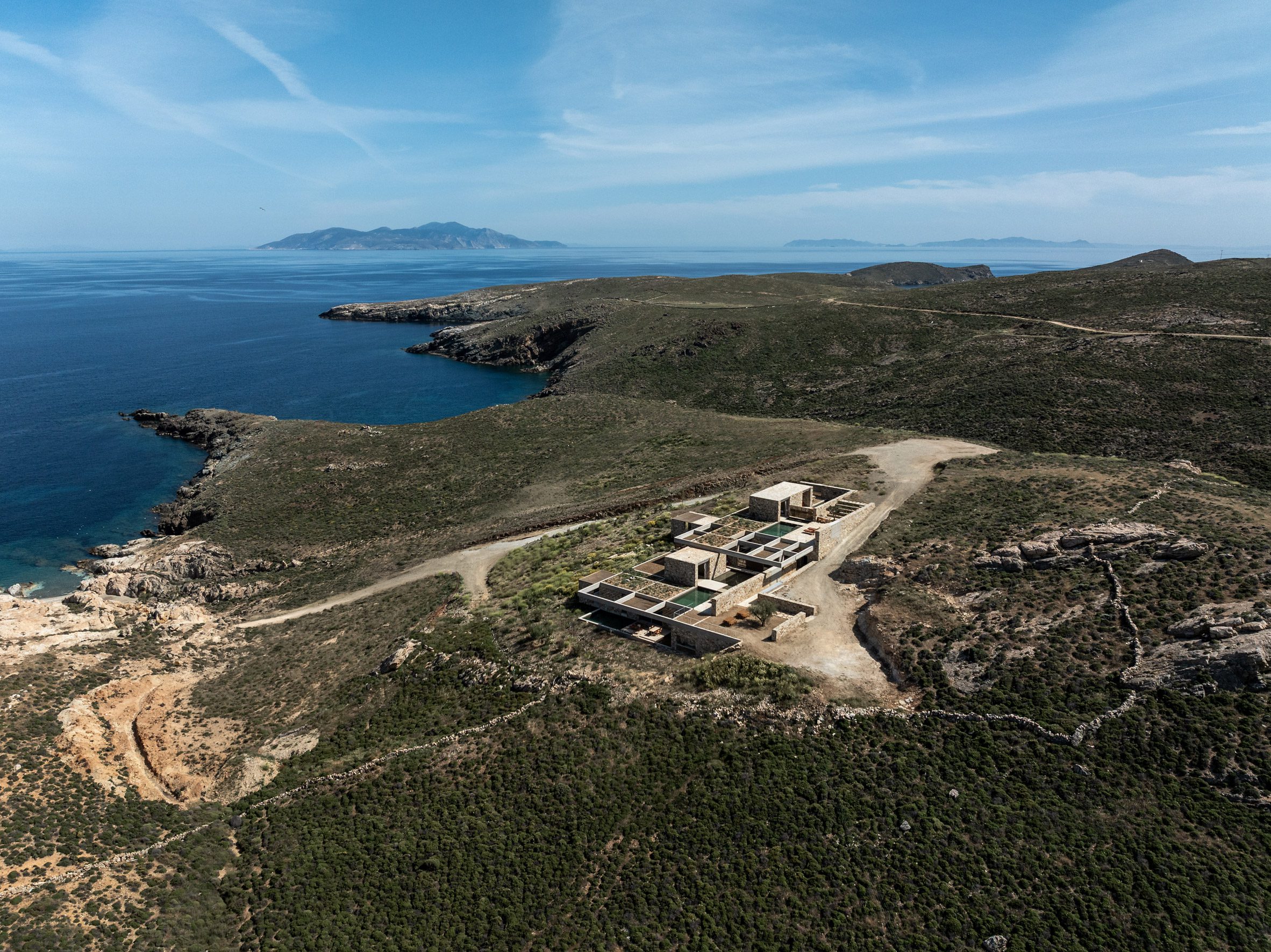 Vista aérea de la casa de huéspedes Perma en una ladera costera con vistas al mar Egeo