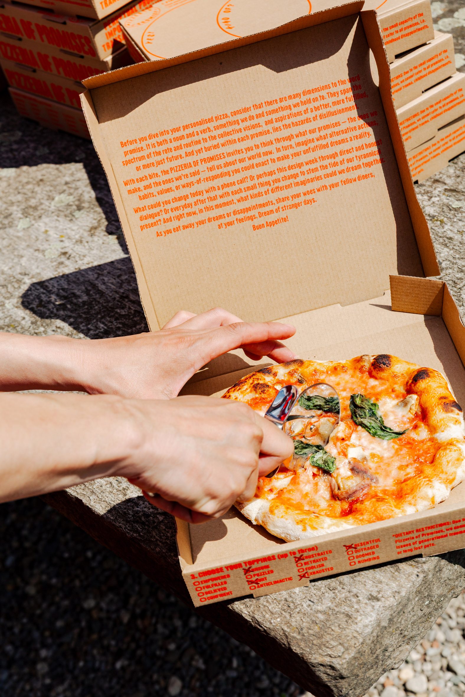 Foto de un hombre cortando pizza italiana en una caja decorada con un texto en rojo brillante
