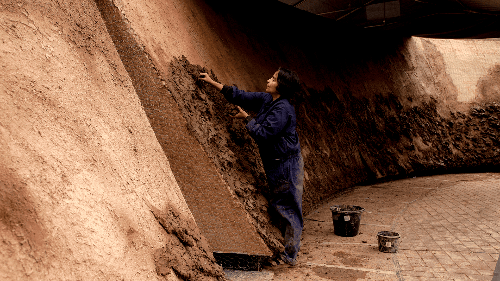 Artist Delcy Morelos applies earth to structure