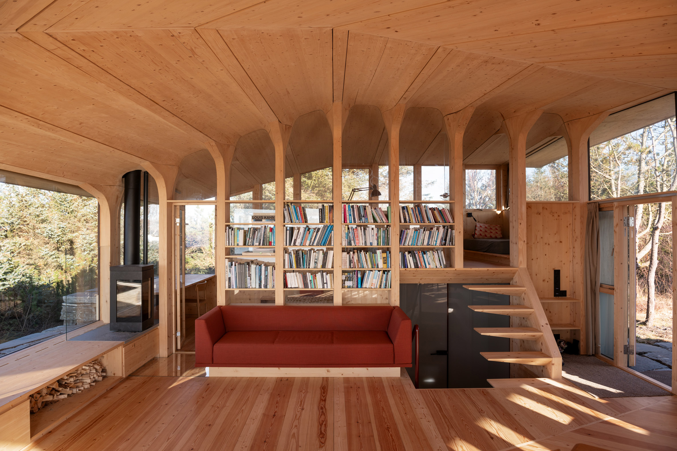 Interior showing built-in bookshelves, a fireplace and timber columns incorporating shelving and stairs
