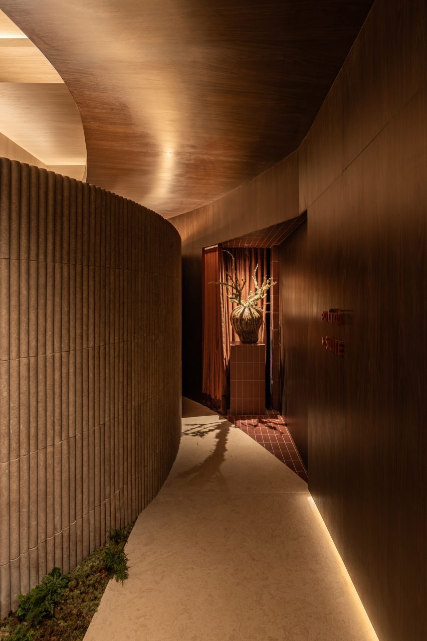 A corridor defined by a curved, fluted-tile partition