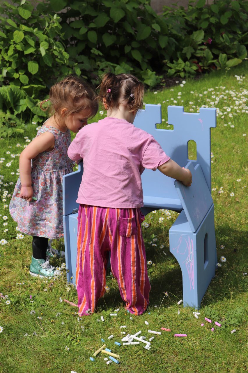 Two girls unfolding a blue chair