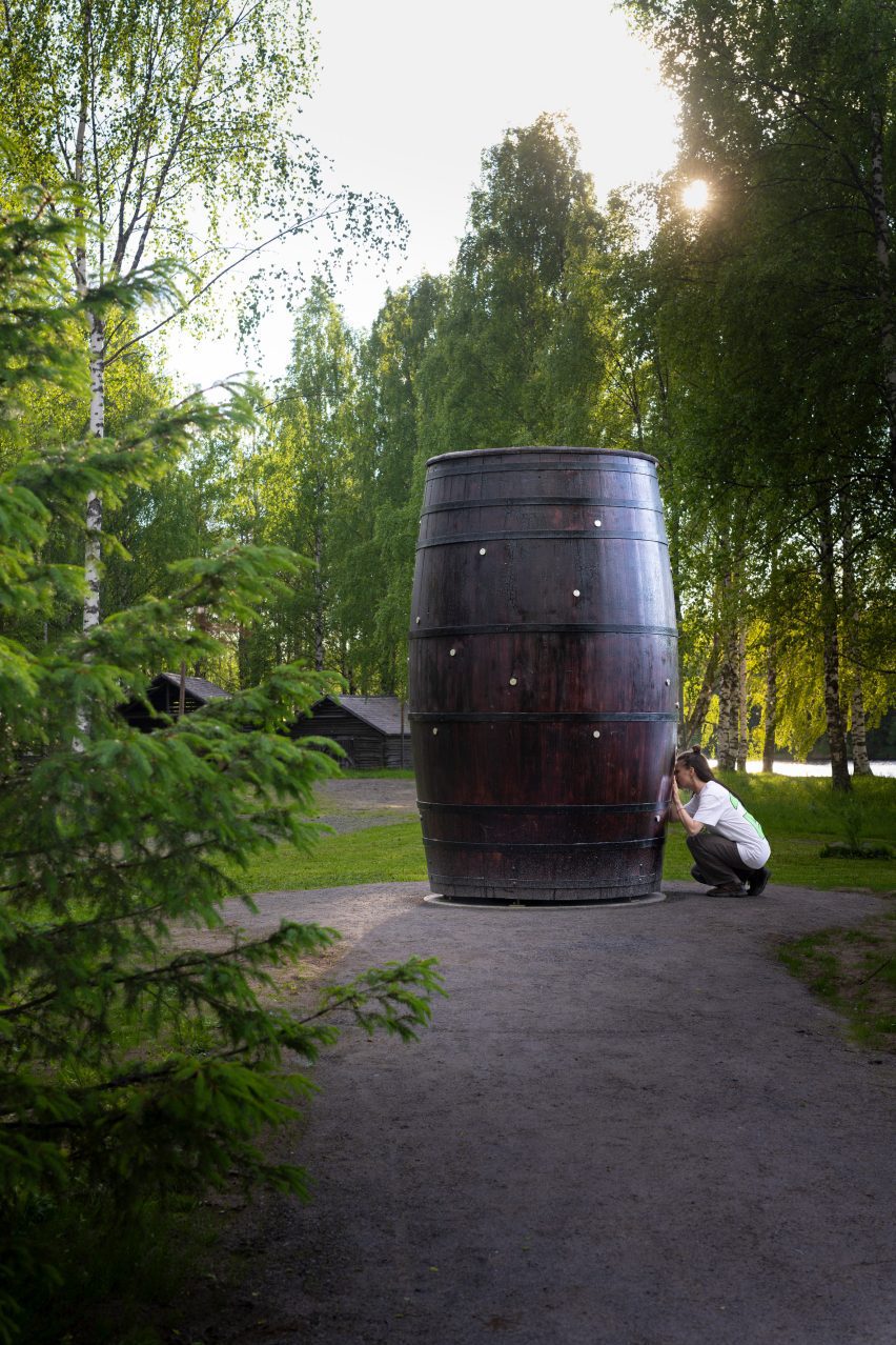 Photo of a person kneeling to peer into an eyehole on Takahiro Iwasaki three-metre-tall barrel artwork Architectural Snowflakes: Letters from Heaven