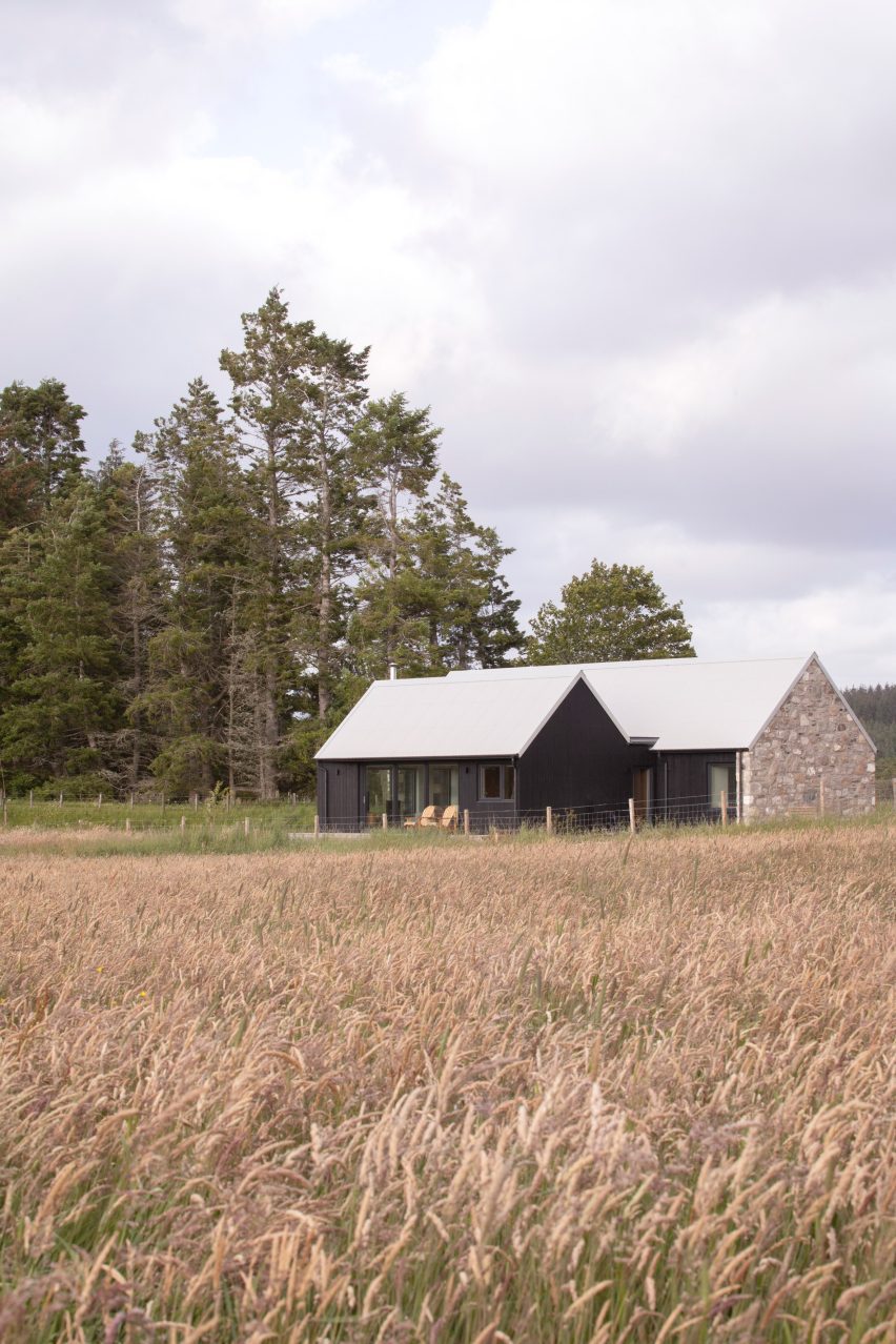 The restored granite cottage viewed across long grasses in the Scottish Highlands