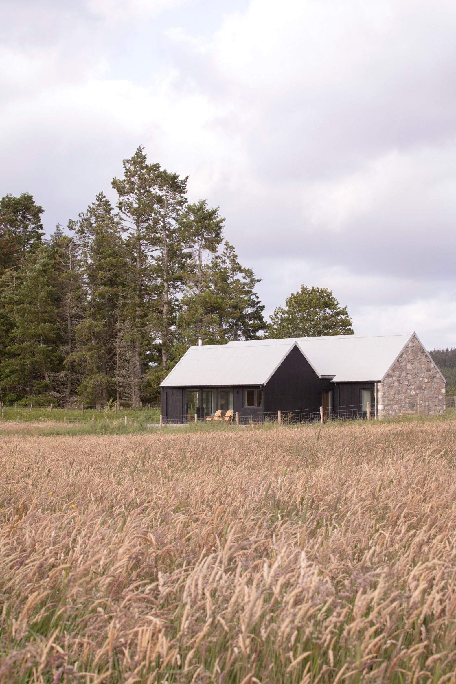 The restored granite cottage viewed across long grasses in the Scottish Highlands