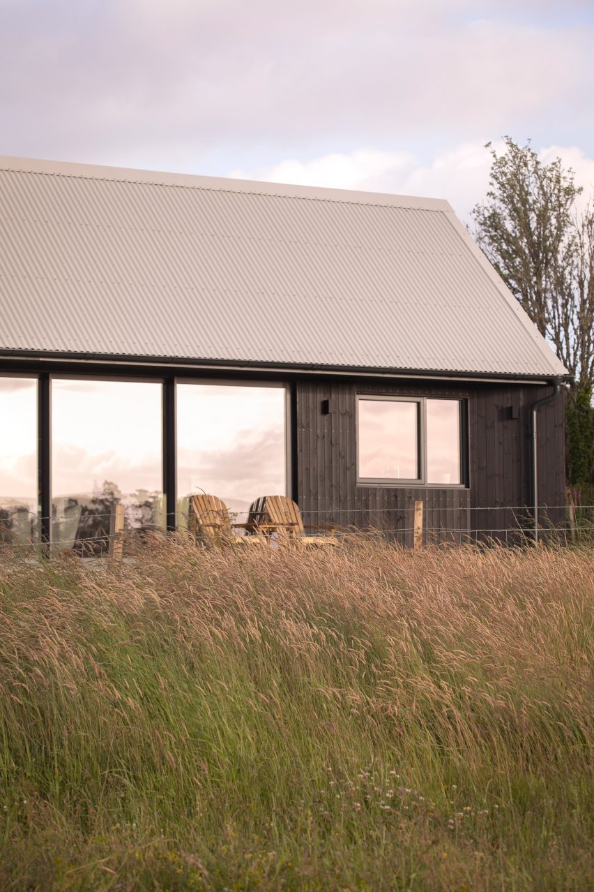 Blackened-larch extension with large sliding glass doors opening onto a raised patio