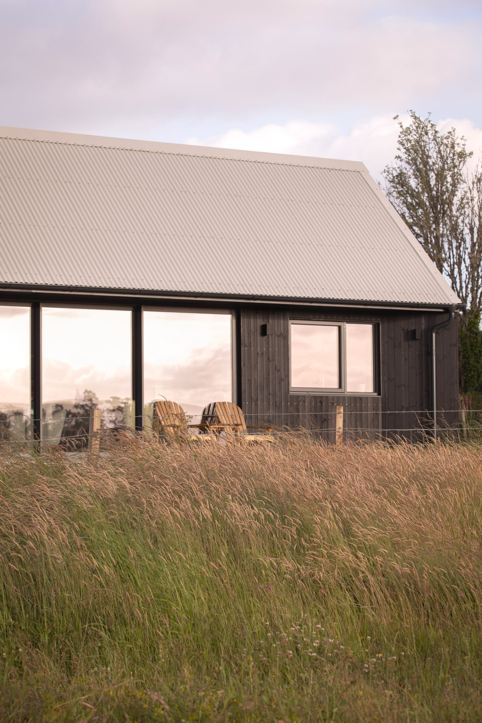 Blackened-larch extension with large sliding glass doors opening onto a raised patio