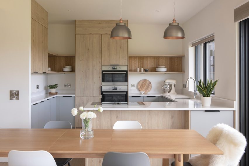 Kitchen with pale oak cabinetry, a muted blue island and timber dining table