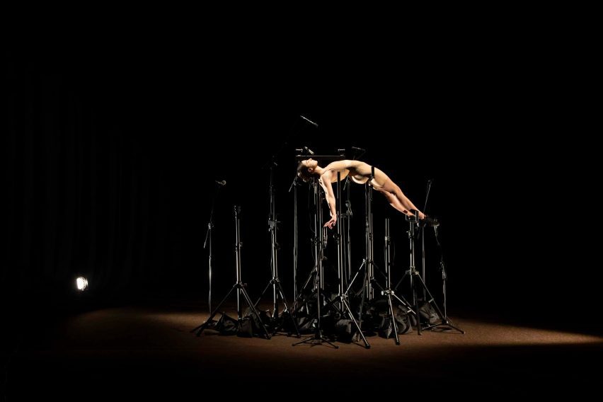 Model posing on top of a series of black tripod-like stands