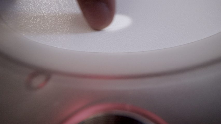 Close-up photo of a finger sliding a white dot across a circular white touchscreen on the Imago device