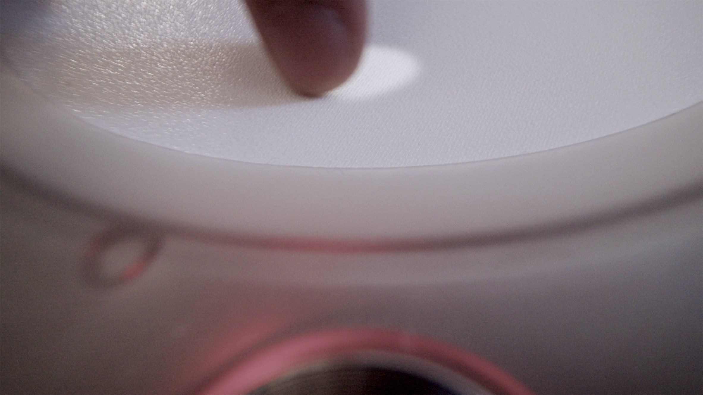 Close-up photo of a finger sliding a white dot across a circular white touchscreen on the Imago device