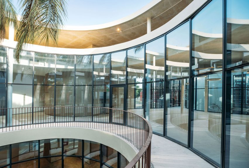 Curved glazed walkway overlooking a circular courtyard beneath the overhanging concrete roof