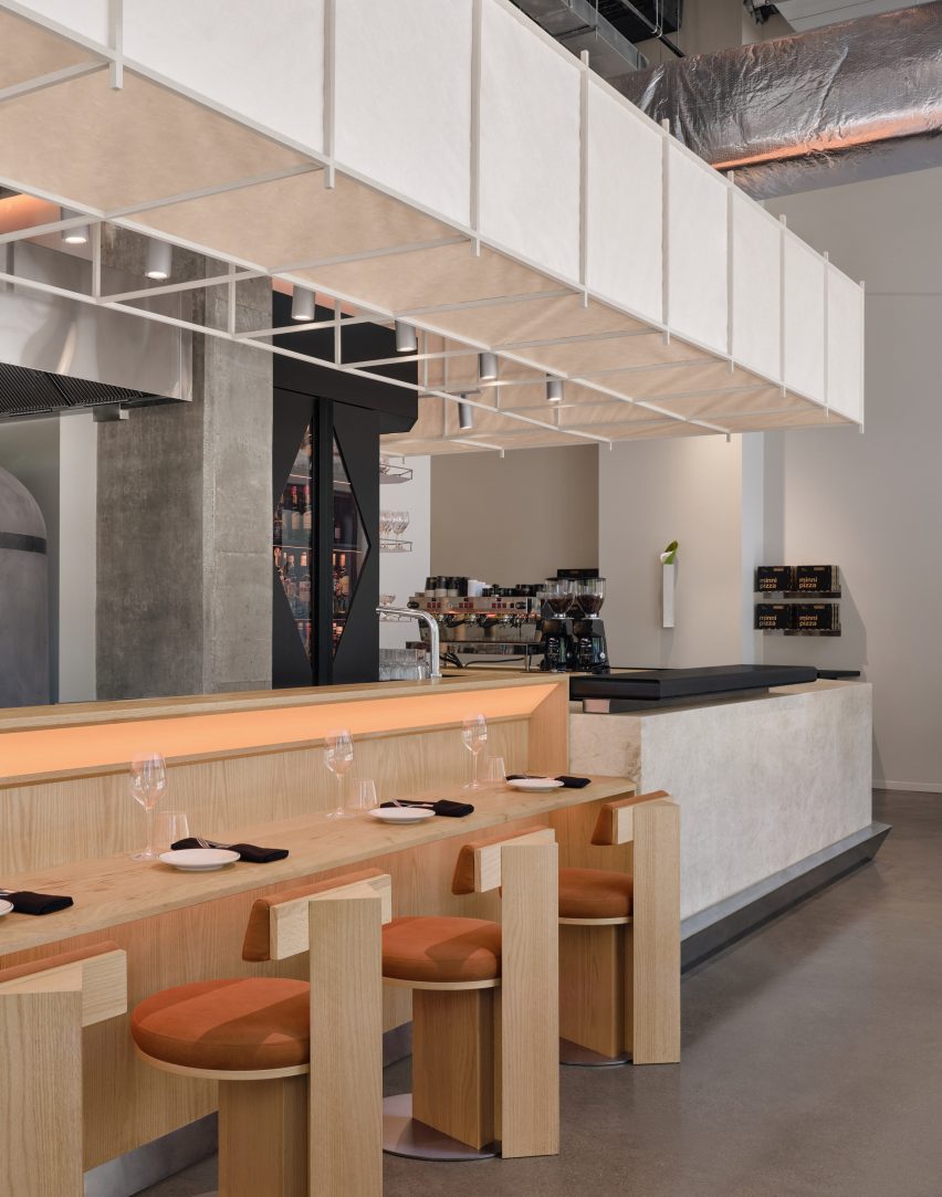 A pale stone-clad cafe counter drops in height to become an omakase-style ledge